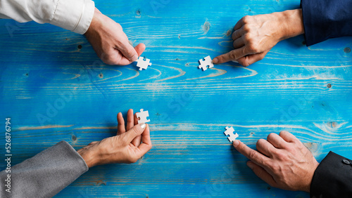 Hands of four business people, male and female, placing puzzle pieces in a circle photo