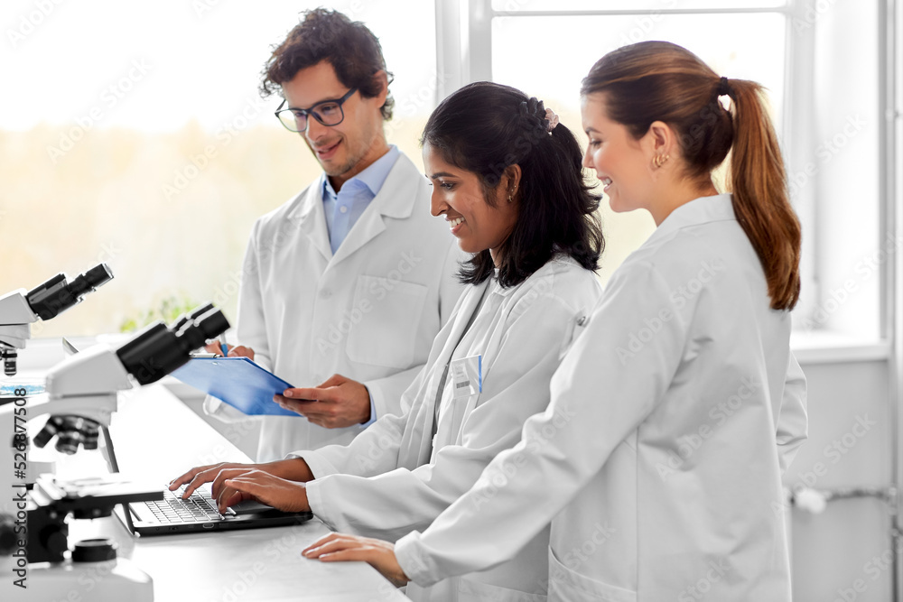 science research, work and people concept - international team of scientists with microscopes and laptop computer working in laboratory science research, work and people concept - international team of scientists with microscopes and laptop computer working in laboratory