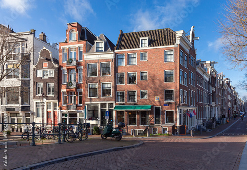 Beautiful old houses on the city waterfront of Amsterdam on a sunny day.