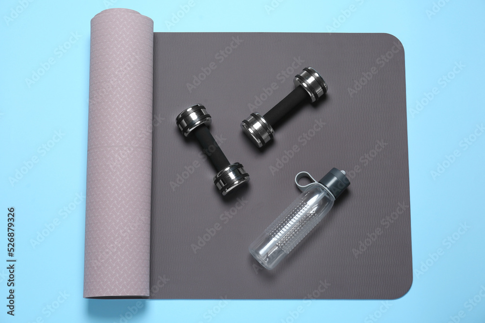Exercise mat, dumbbells and bottle of water on light blue background, top view Exercise mat, dumbbells and bottle of water on light blue background, top view