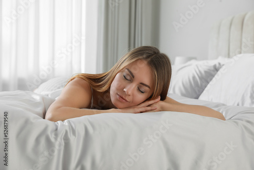 Beautiful woman sleeping on comfortable bed with silky linens