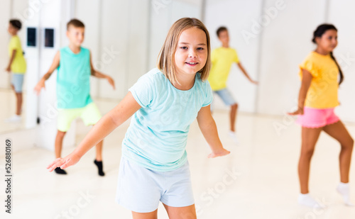 Fototapeta Naklejka Na Ścianę i Meble -  Girl, together with other children, learns modern hip-hop dance moves in class