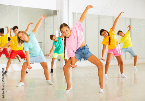 Group of kids training modern dance moves together in studio.
