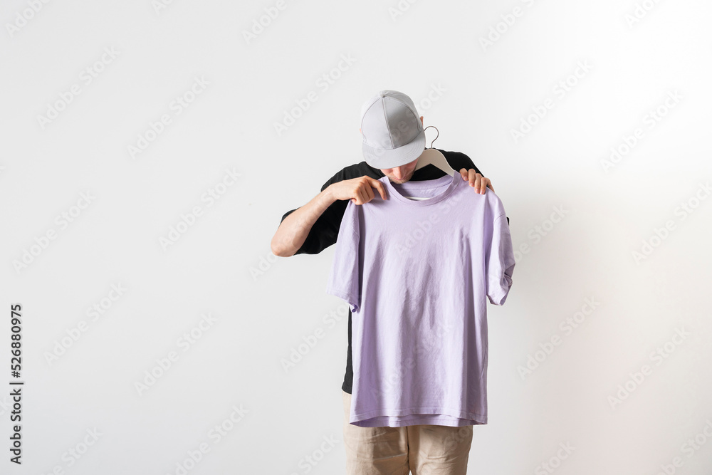 young guy trying on new clothes, isolated on pastel background young guy trying on new clothes, isolated on pastel background