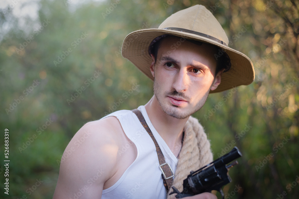 Fototapeta premium Adventurer man with the handgun in the jungle thicket concept.