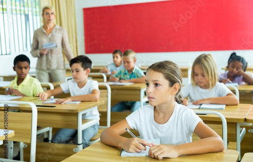 Young girl is sitting at the desk in the classroom elementary school