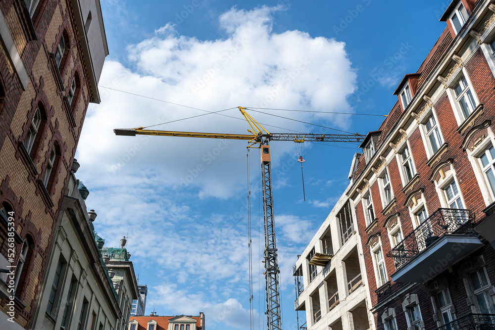 Construction site with crane against blue sky. Building under construction in the old city. Industrial background