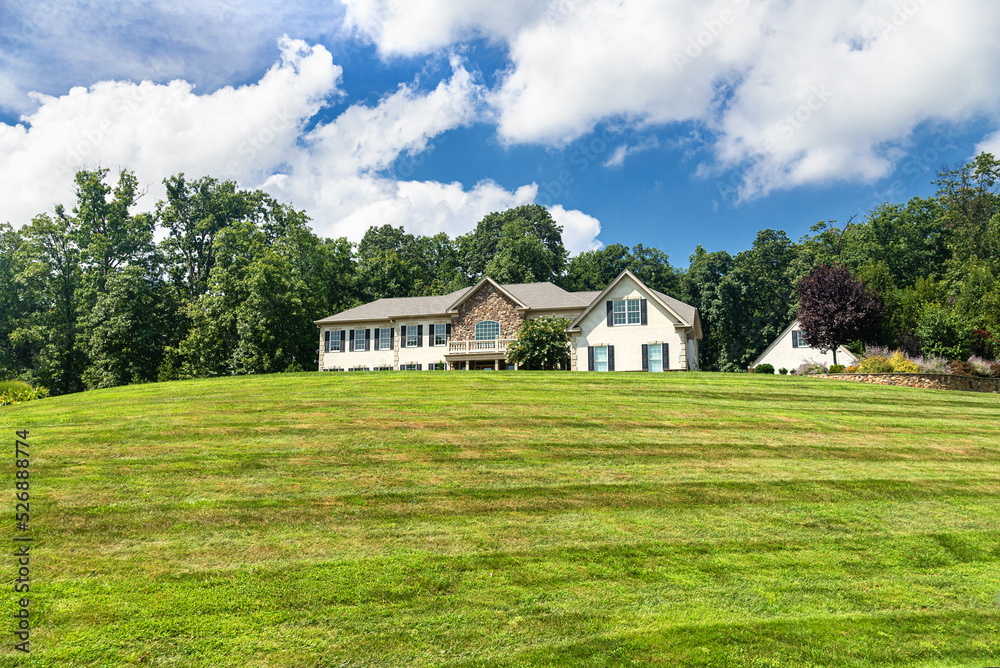 Large country house and summer landscape with  perfect lawn. Blue sky and white clouds.