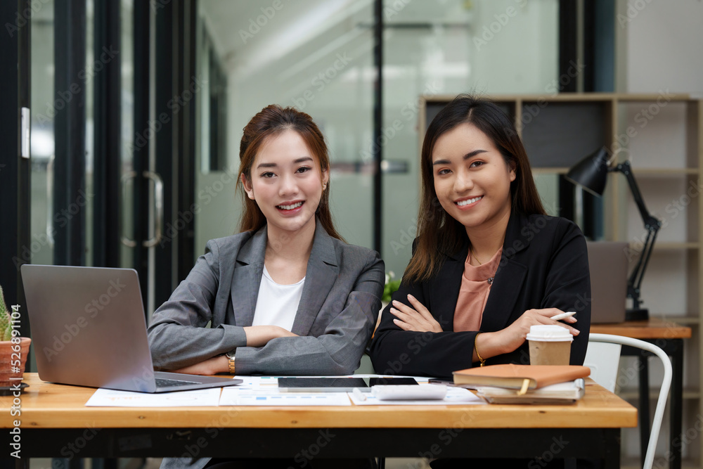 Two Positive Asian secretary smiling to camera during meeting at office. Two Positive Asian secretary smiling to camera during meeting at office.