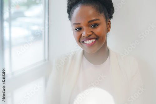 Close up portrait of a smiling african-american woman looking at camera while enjoying relaxing in the city cafe. Small business concept. Break for refreshment.