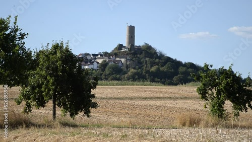 The castle ruin of Vetzberg, Germany behind a few trees and dried out grain fields on a sunny evening photo