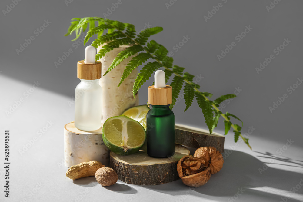 Composition with bottles of essential oil, walnuts, lime and fern leaf on light background Composition with bottles of essential oil, walnuts, lime and fern leaf on light background