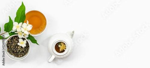 jasmine tea in a cup and kettle for dietary nutrition, jasmine branches with flowers in the corners of the frame, top view, banner
