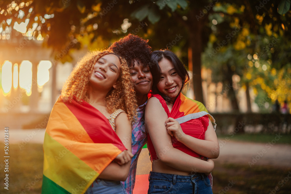 Lesbian women with lgbt flag outdoors