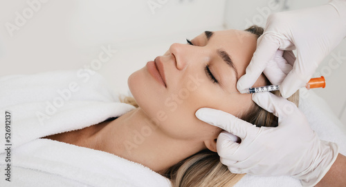 Beautiful woman during facial mesotherapy for smoothing of mimic wrinkles around eyes with beautician. Anti-aging injections for rejuvenation and lift skin