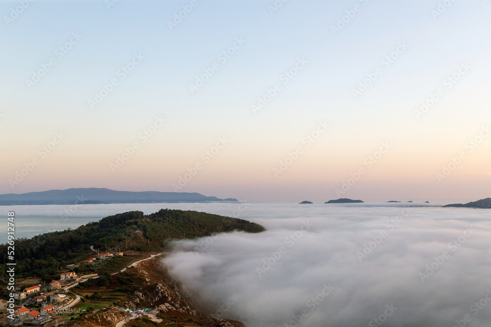 Una lengua de tierra penetra en el mar cubierto por una densa niebla. Cabo Home, Morrazo, Galicia, España.