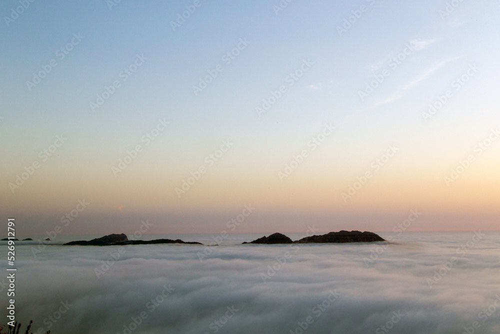 Las Islas Cíes sobresalen sobre un mar de niebla al atardecer. Ría de Vigo, Galicia, España.