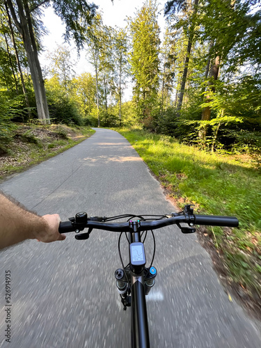 First-person view cycling in the forest. Close-up of a mountain bike handlebar. Summertime outdoor leisure sport activity concept.