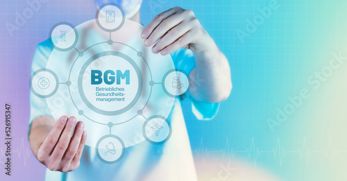 BGM (Betriebliches Gesundheitsmanagement). Medizin in der Zukunft. Arzt hält virtuelles Interface mit Text und Icons im Kreis.