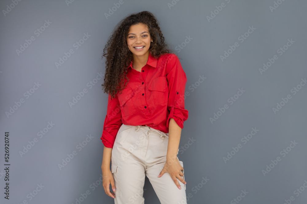 Young woman in red shirt standing against grey wall Young woman in red shirt standing against grey wall