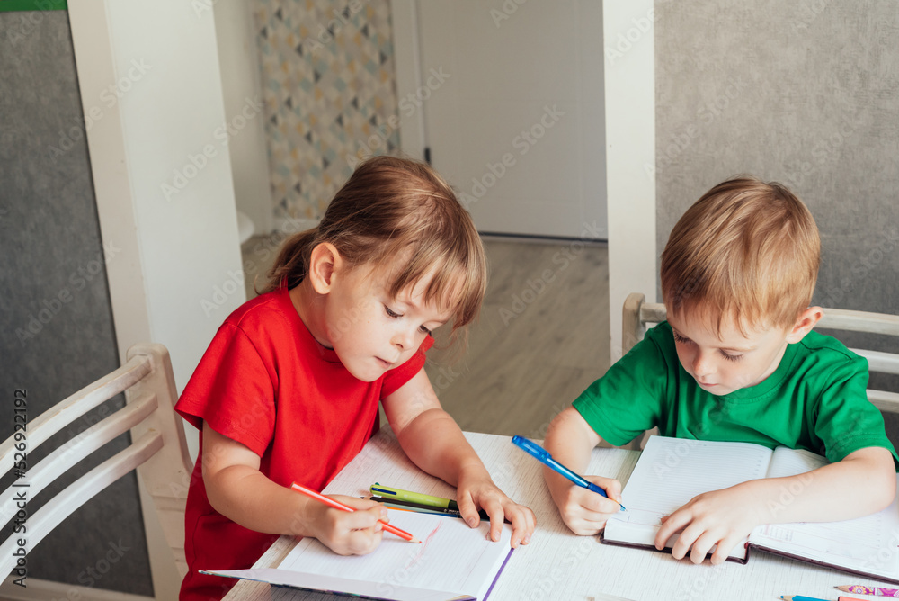 Children sit at the table and write in notebooks Children sit at the table and write in notebooks