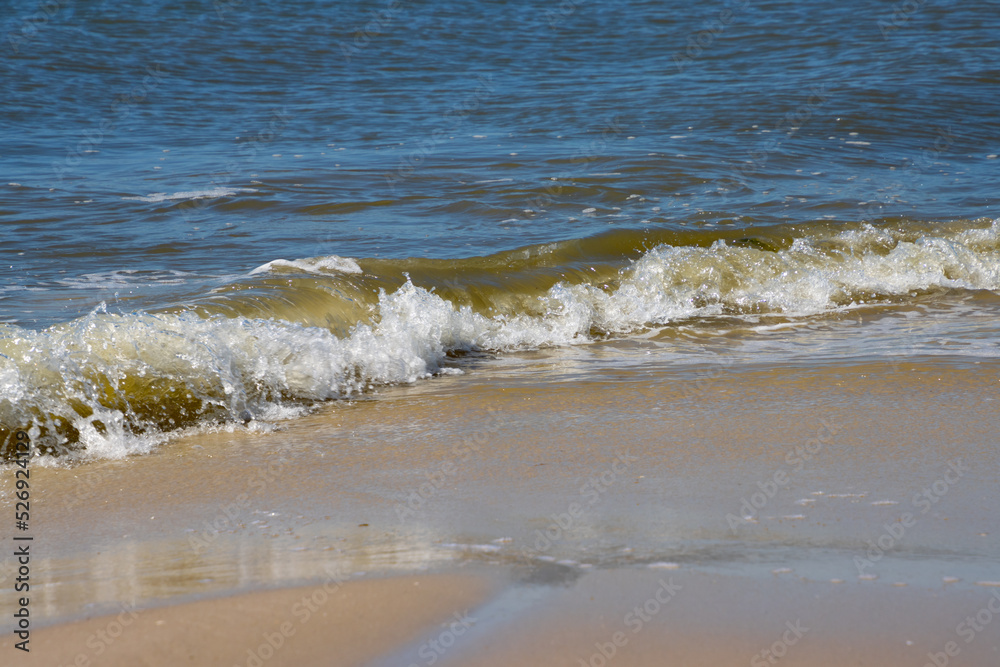 Breaking waves at a sandy beach on a sunny day