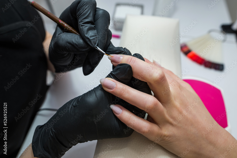 The manicurist covers the client's nails with red varnish. Manicure in a beauty salon.