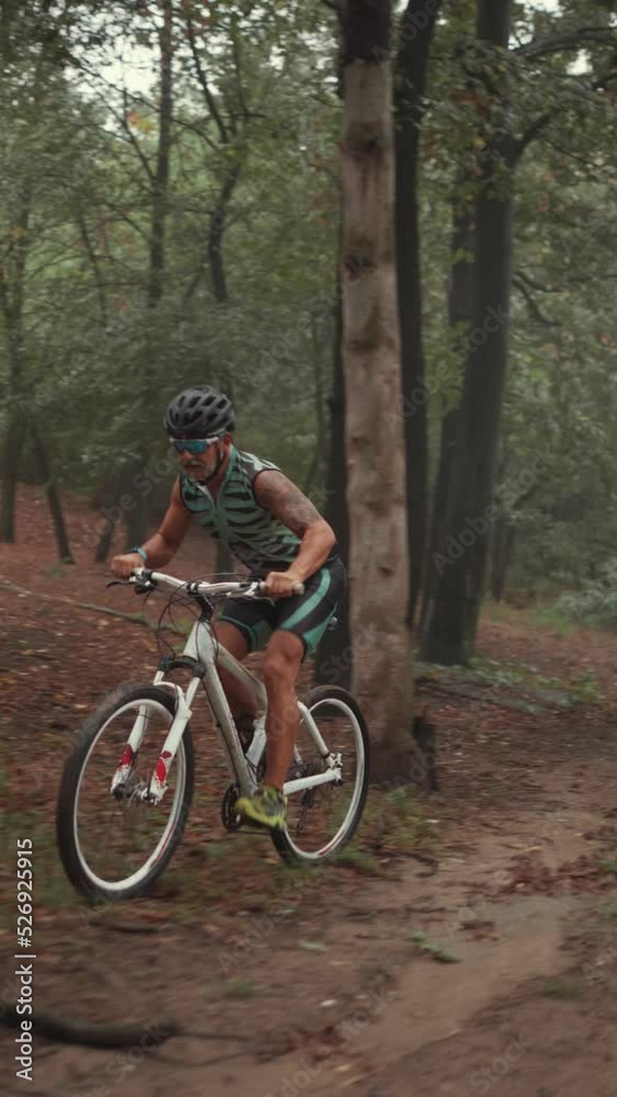 Slow motion shot of an extreme adult cyclist riding a bike in the forest on a cloudy day Slow motion shot of an extreme adult cyclist riding a bike in the forest on a cloudy day