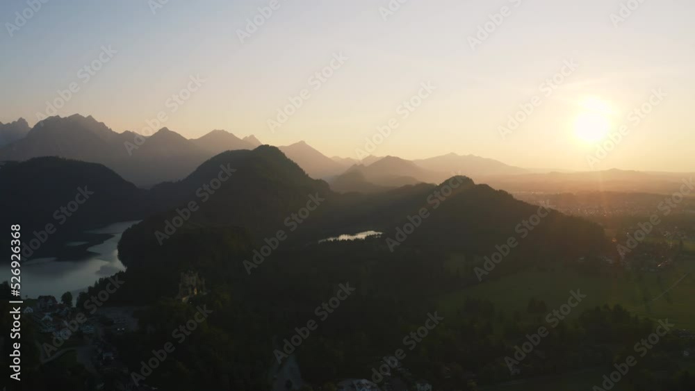 Aerial view overlooking the lake Alpsee and the Hohenschwangau Castle, sunrise in Germany - circling, drone shot Aerial view overlooking the lake Alpsee and the Hohenschwangau Castle, sunrise in Germany - circling, drone shot