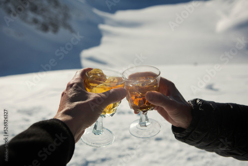 Close up POV hands of friends toasting apres-ski cocktails in snow
 photo