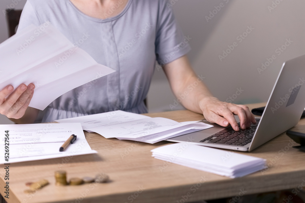 A woman sits at a table and looks through papers, receipts, utility bills.