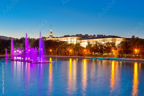 Colorful Illuminated Fountains on the Svisloch River During Summer Night Against Blue Sky Night View of Minsk City Center and Famous National Landmark of Belarus.