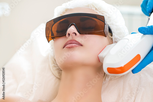 Young Caucasian Winsome Woman Getting IPL Laser and Ultrasound Facial Treatment in Modern Medical Spa Center As Skin Rejuvenation Concept photo