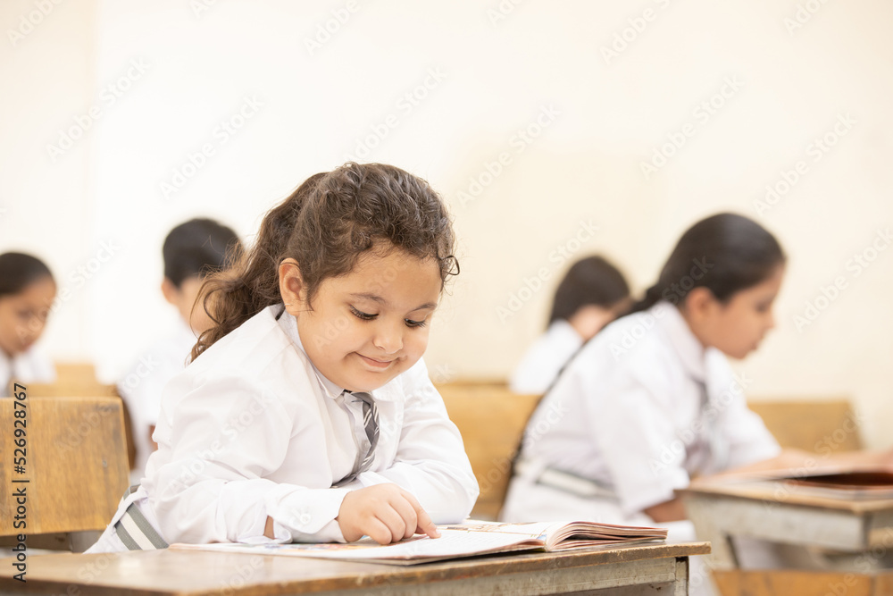 Indian elementary school students sitting at desk in classroom with writing in notebook with pencil, Examination and test, Girl Education concept. Indian elementary school students sitting at desk in classroom with writing in notebook with pencil, Examination and test, Girl Education concept.