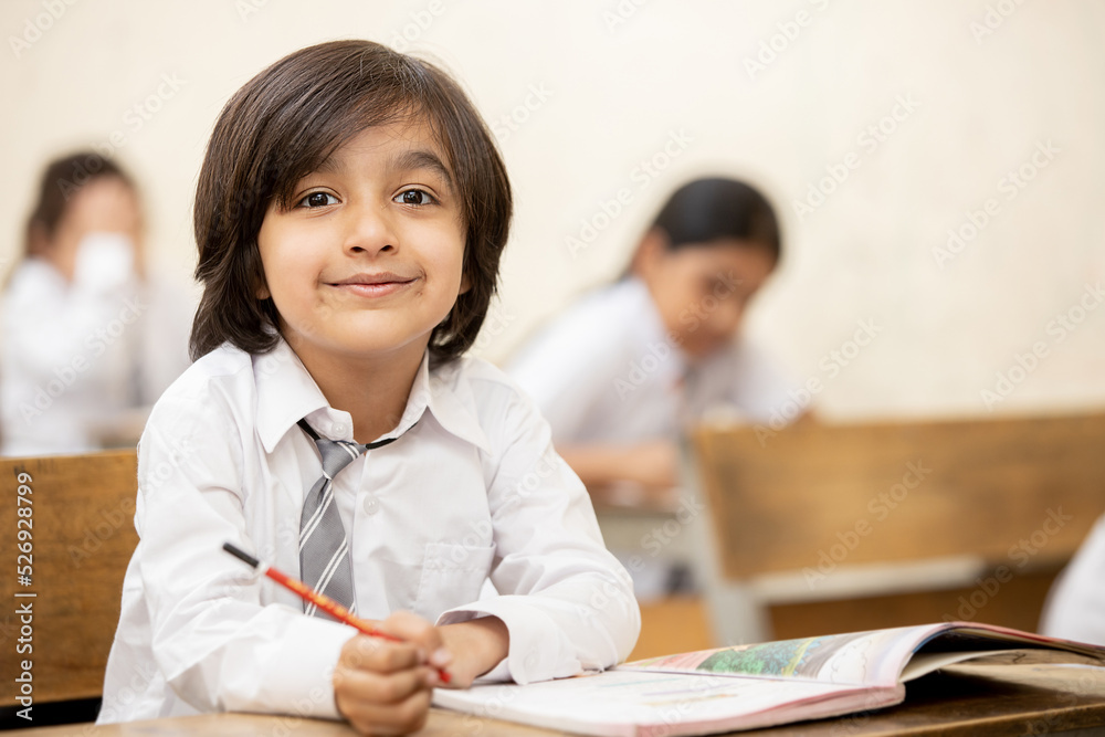 Portrait of happy indian school sitting at desk in classroom, school kids with pens and notebooks writing test Elementary school, Education concept. Portrait of happy indian school sitting at desk in classroom, school kids with pens and notebooks writing test Elementary school, Education concept.
