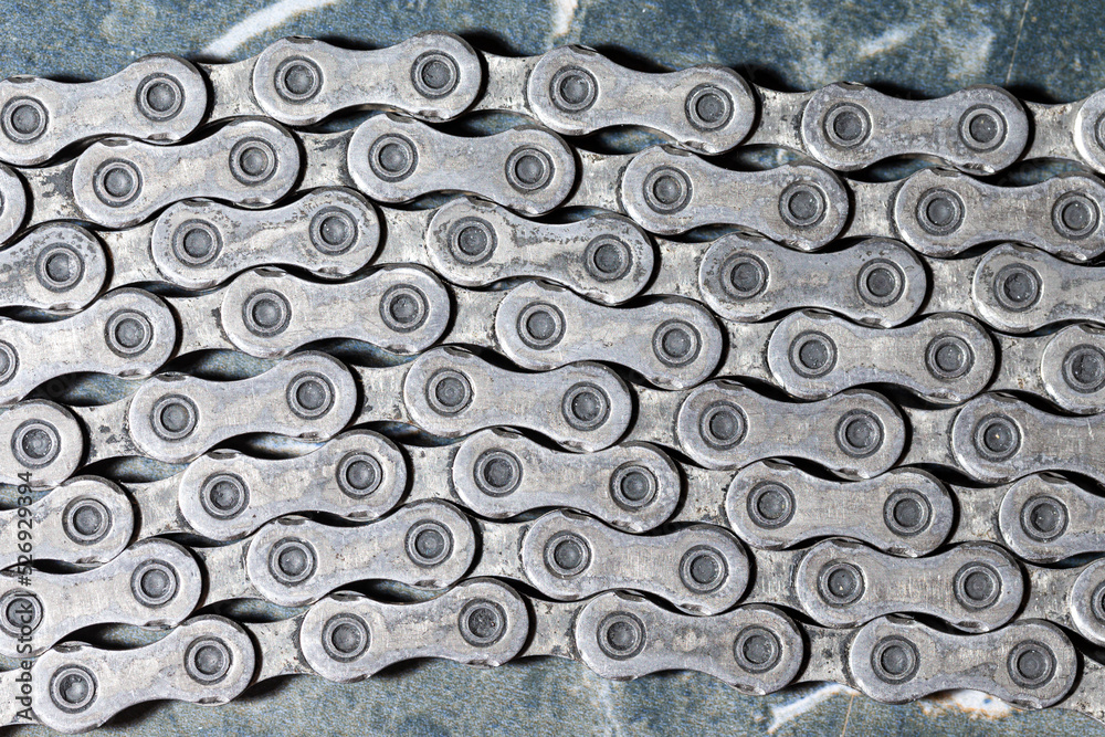 Closeup of Shiny Dirty Greasy Oiled Bicycle Chain As A Part of Metal Bicycle Equipment On Grey Tile Stony Background With Contrast Details Closeup of Shiny Dirty Greasy Oiled Bicycle Chain As A Part of Metal Bicycle Equipment On Grey Tile Stony Background With Contrast Details