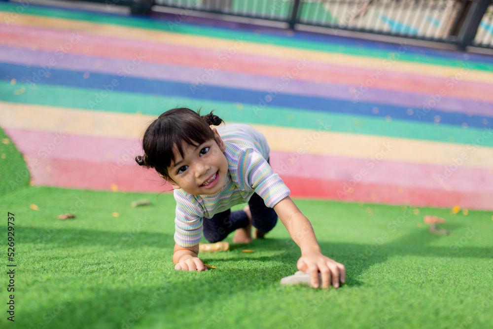 Cute Asian girl having fun trying to climb on artificial boulders at schoolyard playground, Little girl climbing up the rock wall, Hand Eye Coordination, Skills development
