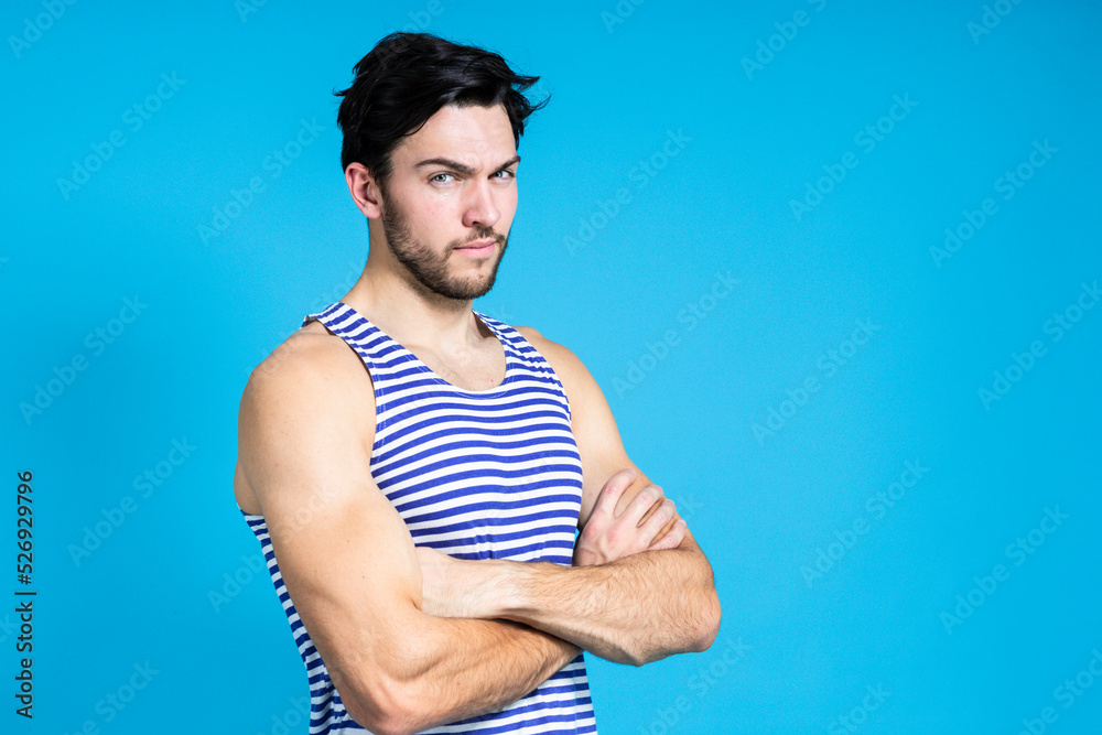 Caucasian Handsome Brunet Man in Striped Underware During Early Morning Posing With Hands Folded In Front Against Seamless Blue Background. Caucasian Handsome Brunet Man in Striped Underware During Early Morning Posing With Hands Folded In Front Against Seamless Blue Background.