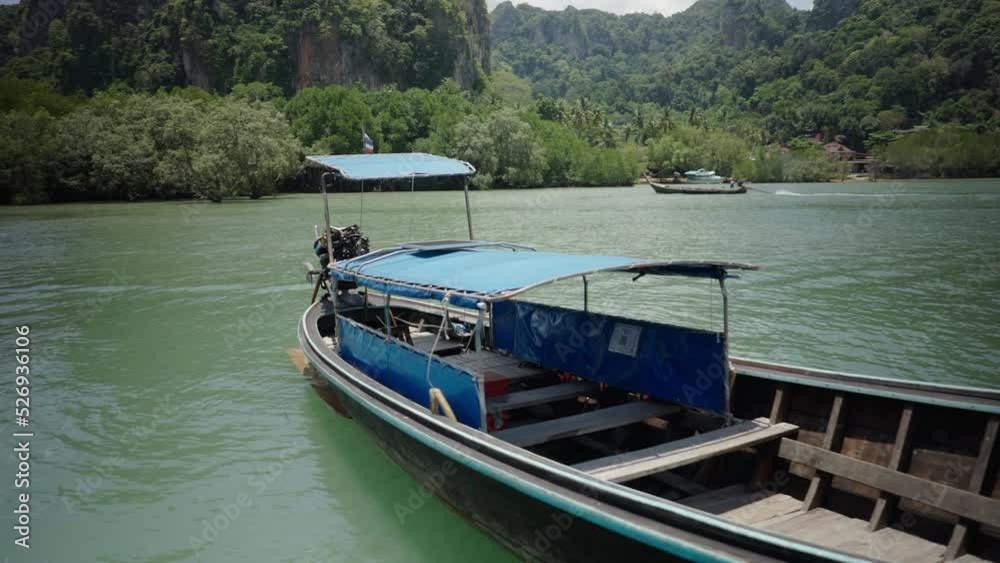 Thai long-tail passenger boat for travel guided island hopping tours floating anchored at Railay Beach, Thailand Thai long-tail passenger boat for travel guided island hopping tours floating anchored at Railay Beach, Thailand