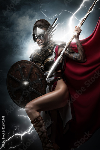 Portrait of violent goddes dressed in armor holding sword against heaven and thunderstorm. photo