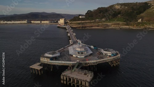 Aerial drone flight around the pier in Llandudno wales showing the amusements and a view of the seafront and mountains photo