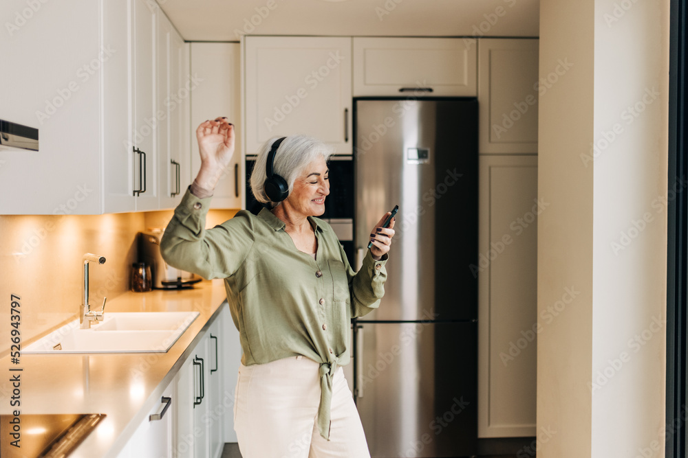 Cheerful senior woman dancing to her favourite music at home Cheerful senior woman dancing to her favourite music at home