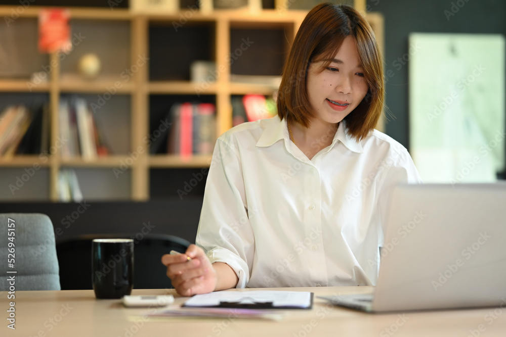 Asian woman creative designer working on new project, checking online information on her laptop Asian woman creative designer working on new project, checking online information on her laptop