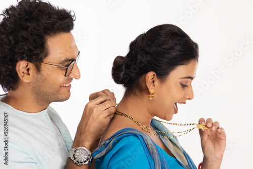 Loving husband wearing mangalsutra to his wife photo