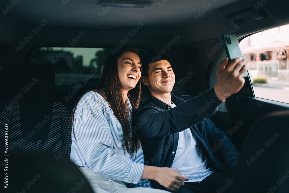 Loving couple travelling in the backseat of a cab. Smiling man and woman going out in a taxi.