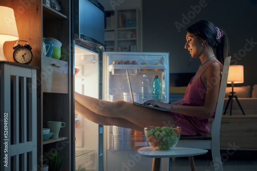 Woman cooling herself in front of the open fridge photo