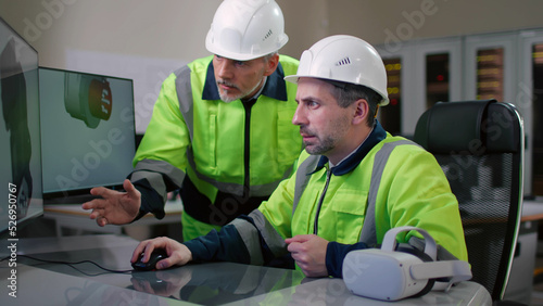 Industrial engineers in protective uniform discuss 3d blueprint of machine detail on computer