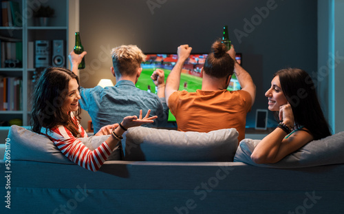 Girls talking while men are watching soccer on TV