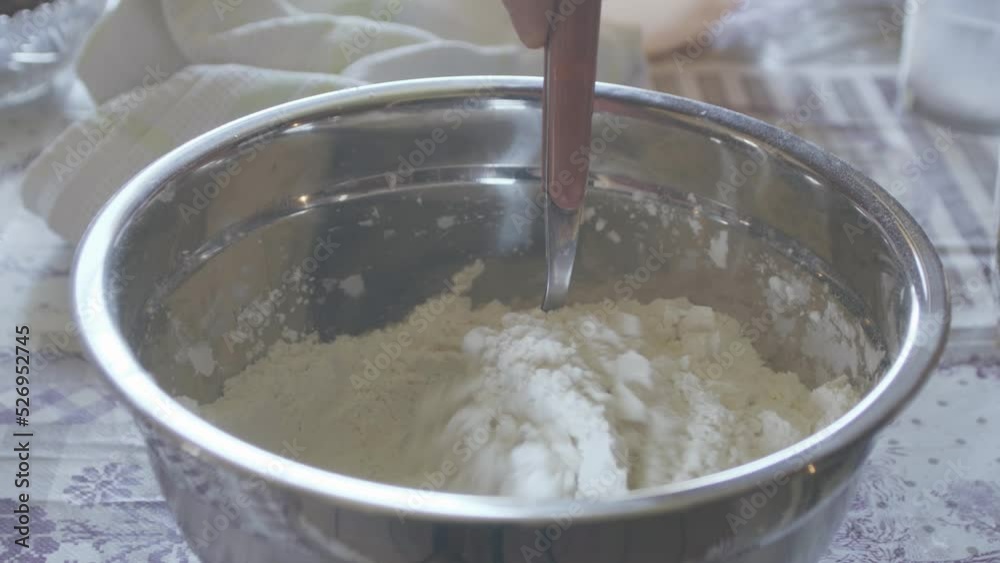 Detail of flour and starch mixed with a red spoon inside a metal bowl, preparation of a vanilla and chocolate cake Detail of flour and starch mixed with a red spoon inside a metal bowl, preparation of a vanilla and chocolate cake