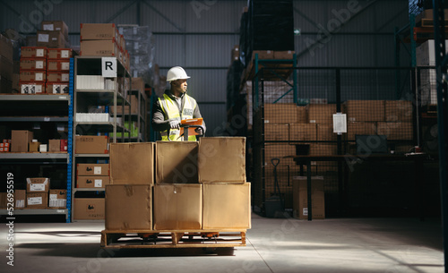 Warehouse employee holding a loaded pallet jack in a logistics centre photo